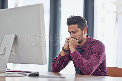 Buy stock photo Cropped shot of a handsome young businessman looking thoughtful while working on a computer in a modern office