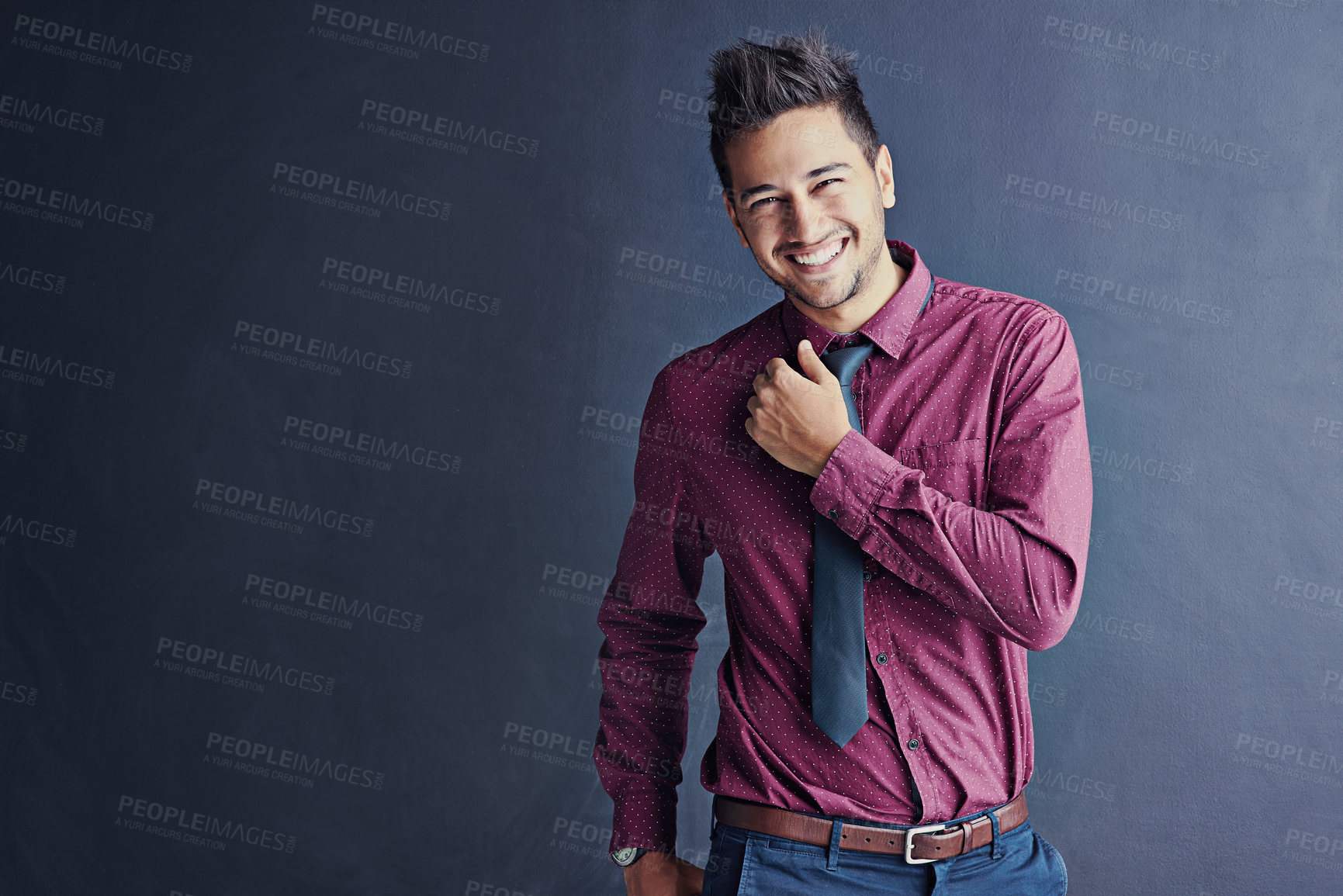 Buy stock photo Studio portrait of a handsome young businessman smiling while standing against a grey background