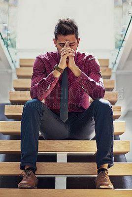 Buy stock photo Shot of a young businessman looking stressed out while sitting on the stairs