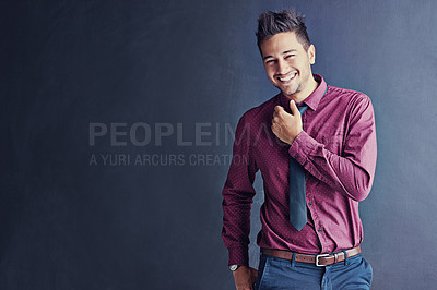 Buy stock photo Studio portrait of a handsome young businessman smiling while standing against a grey background