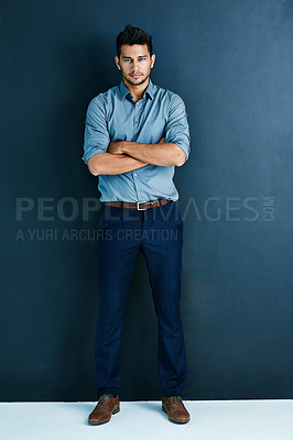 Buy stock photo Studio portrait of a handsome young businessman standing with his arms crossed against a grey background
