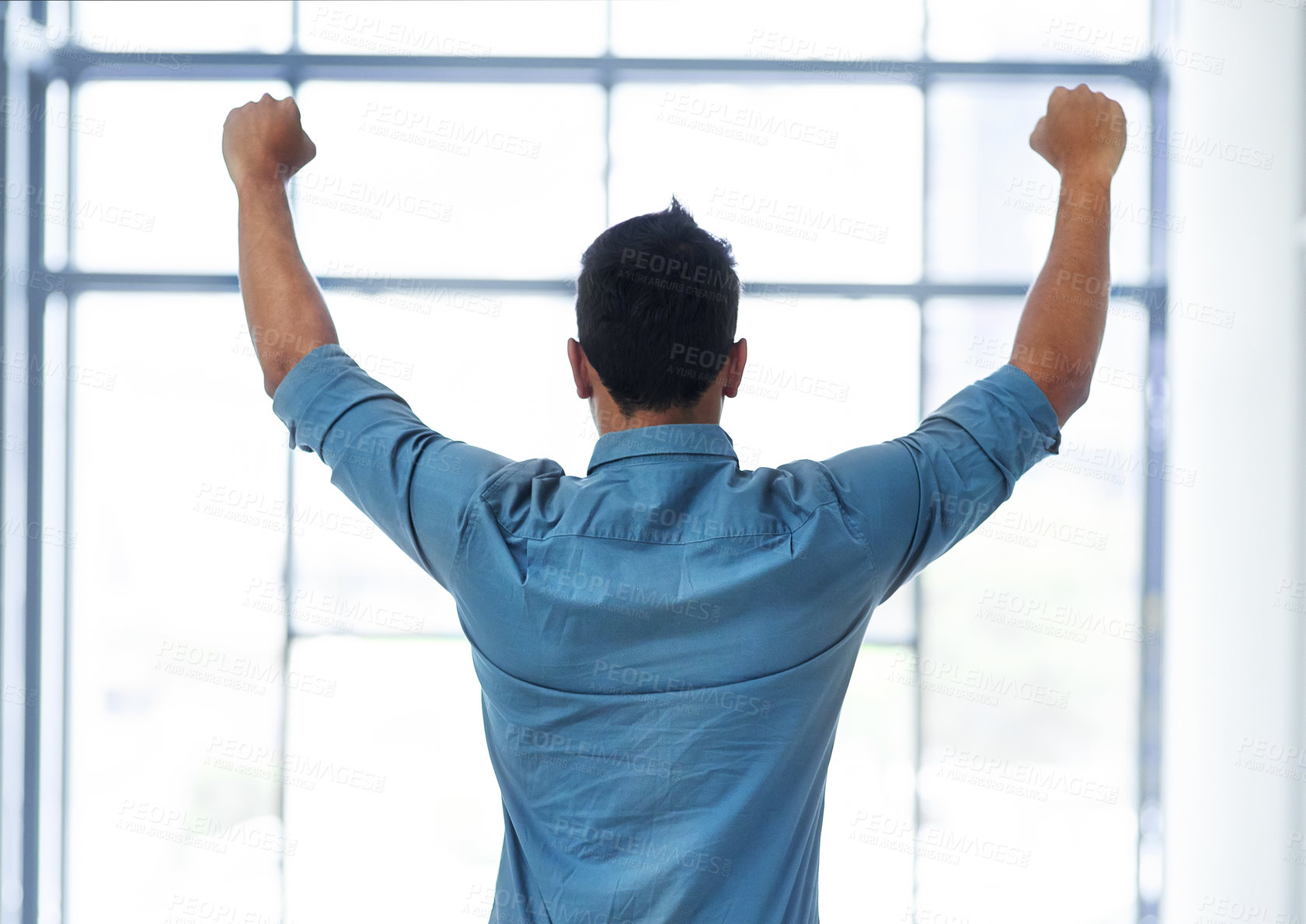 Buy stock photo Rearview shot of an unrecognizable businessman celebrating with his arms raised in a modern office