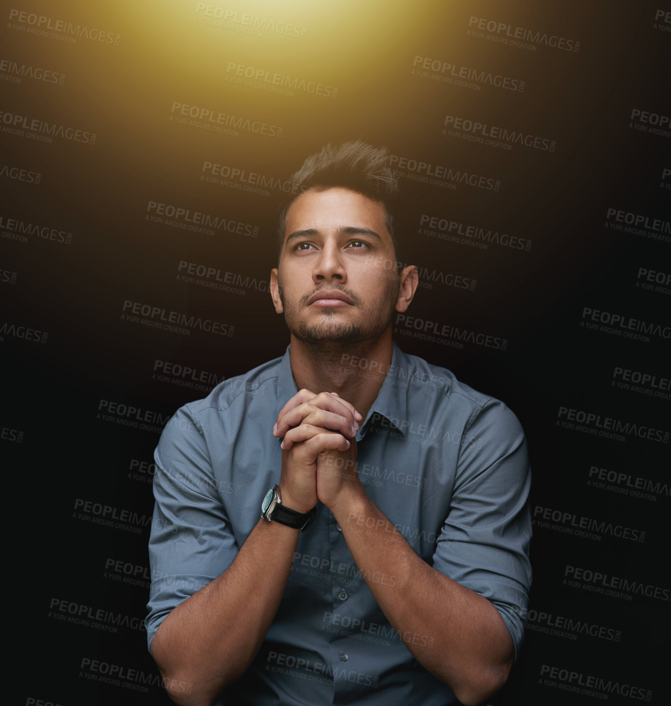 Buy stock photo Cropped shot of a handsome young businessman sitting with his hands together against a black background