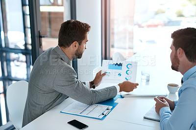 Buy stock photo Cropped shot of two young businessmen going through paperwork together in a modern office