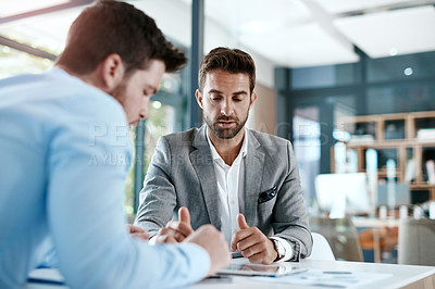 Buy stock photo Cropped shot of two young businessmen using a digital tablet while going through paperwork together in a modern office