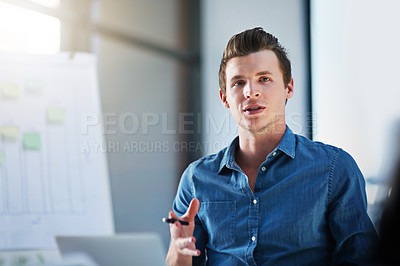 Buy stock photo Shot of a young businessman explaining his ideas to his colleagues in a modern office