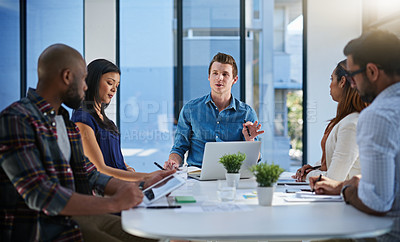 Buy stock photo Shot of a group of young businesspeople discussing ideas with each other during a meeting in a modern office