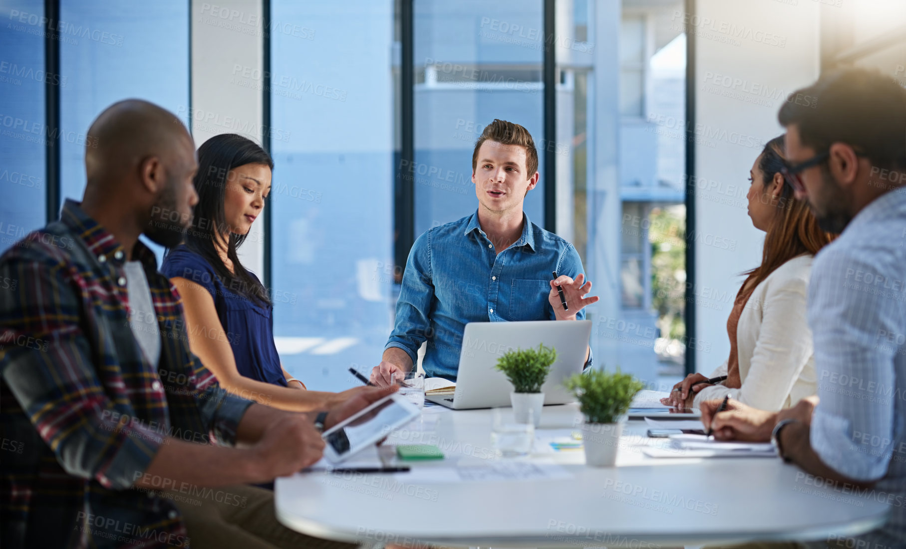 Buy stock photo Shot of a group of young businesspeople discussing ideas with each other during a meeting in a modern office