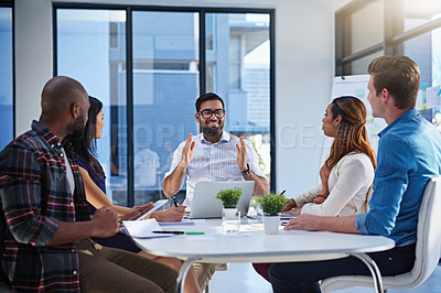 Buy stock photo Shot of a group of young businesspeople discussing ideas with each other during a meeting in a modern office