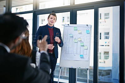 Buy stock photo Shot of a young businessman giving a demonstration on a white board to his colleagues in a modern office