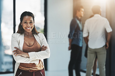 Buy stock photo Portrait of a cheerful businesswoman posing with her arms folded in a modern office with her colleagues in the background