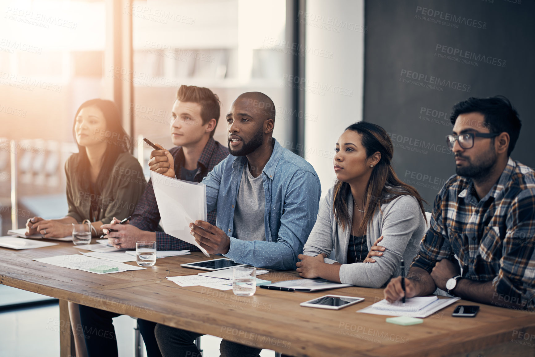 Buy stock photo Shot of a group of young businesspeople having a meeting in a modern office