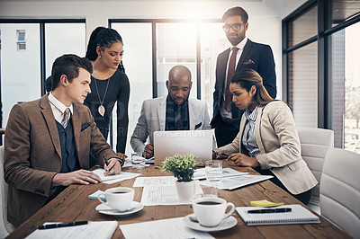 Buy stock photo Shot of a group of young businesspeople using a laptop together during a meeting in a modern office