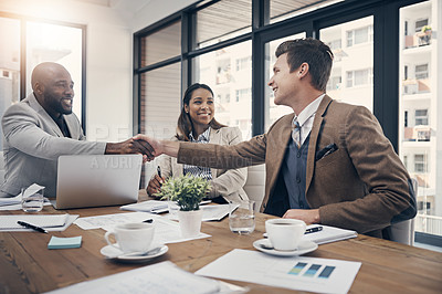 Buy stock photo Shot of young businessmen shaking hands during a meeting in a modern office