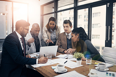 Buy stock photo Shot of a group of young businesspeople using a laptop together during a meeting in a modern office