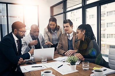 Buy stock photo Shot of a group of young businesspeople using a laptop together during a meeting in a modern office