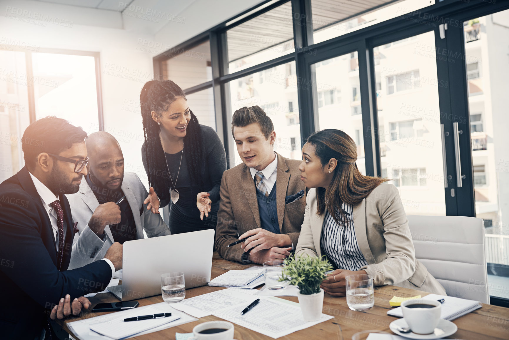 Buy stock photo Shot of a group of young businesspeople using a laptop together during a meeting in a modern office