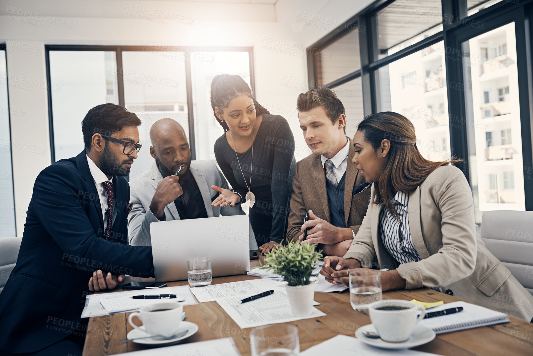 Buy stock photo Shot of a group of young businesspeople using a laptop together during a meeting in a modern office