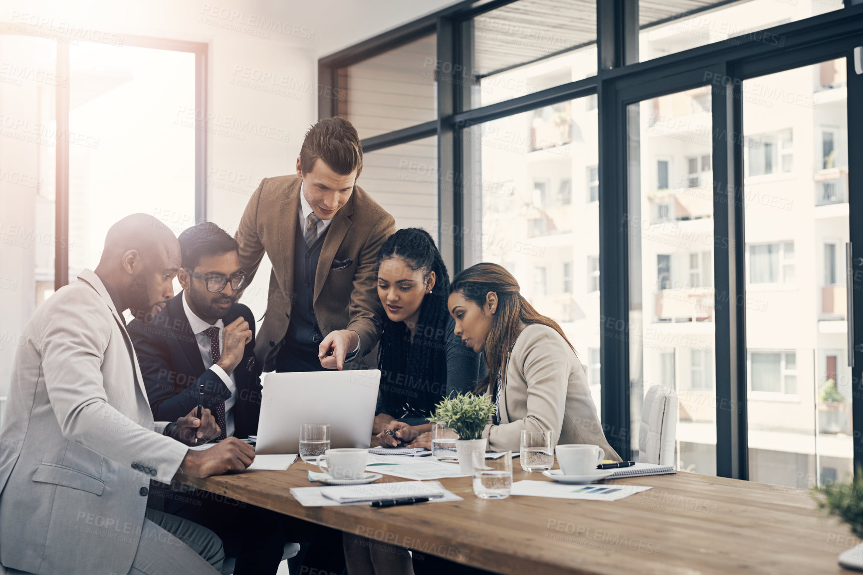 Buy stock photo Shot of a group of young businesspeople using a laptop together during a meeting in a modern office