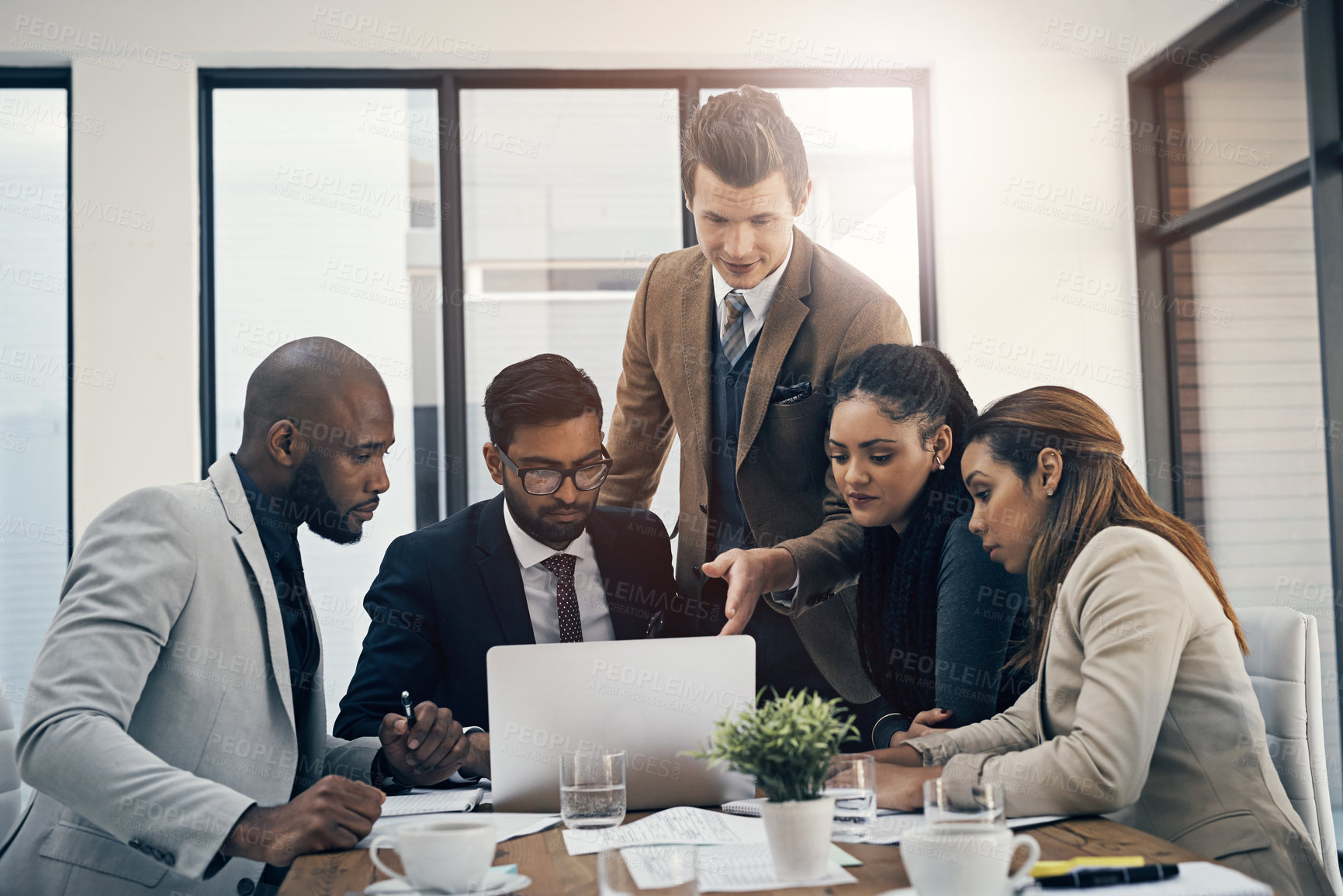 Buy stock photo Shot of a group of young businesspeople using a laptop together during a meeting in a modern office