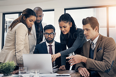 Buy stock photo Shot of a group of young businesspeople using a laptop together during a meeting in a modern office