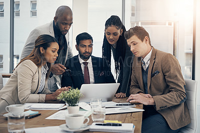 Buy stock photo Shot of a group of young businesspeople using a laptop together during a meeting in a modern office