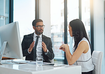 Buy stock photo Cropped shot of two young businesspeople having a discussion while working in a modern office
