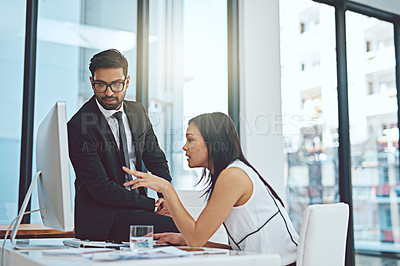 Buy stock photo Cropped shot of two young businesspeople having a discussion while working on a computer in a modern office
