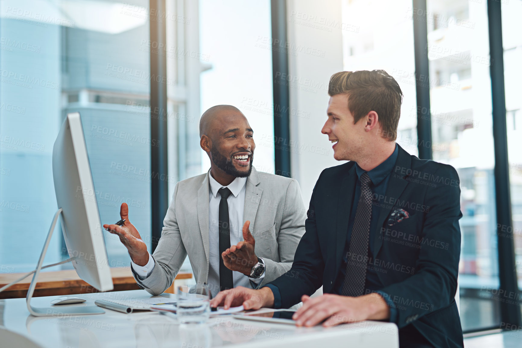 Buy stock photo Cropped shot of two young businessmen having a discussion while working in a modern office