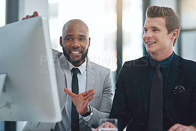 Buy stock photo Cropped shot of two young businessmen having a discussion while working on a computer in a modern office