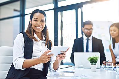 Buy stock photo Cropped portrait of an attractive young businesswoman using a digital tablet in an office with her colleagues in the background