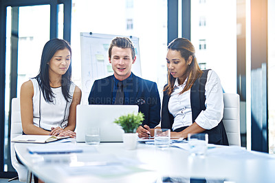 Buy stock photo Cropped shot of a group of young businesspeople having a discussion while using a laptop in a modern office