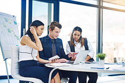 Buy stock photo Cropped shot of a group of young businesspeople having a discussion while using a laptop in a modern office