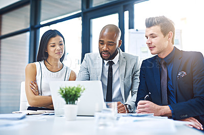 Buy stock photo Cropped shot of a group of young businesspeople having a discussion while using a laptop in a modern office