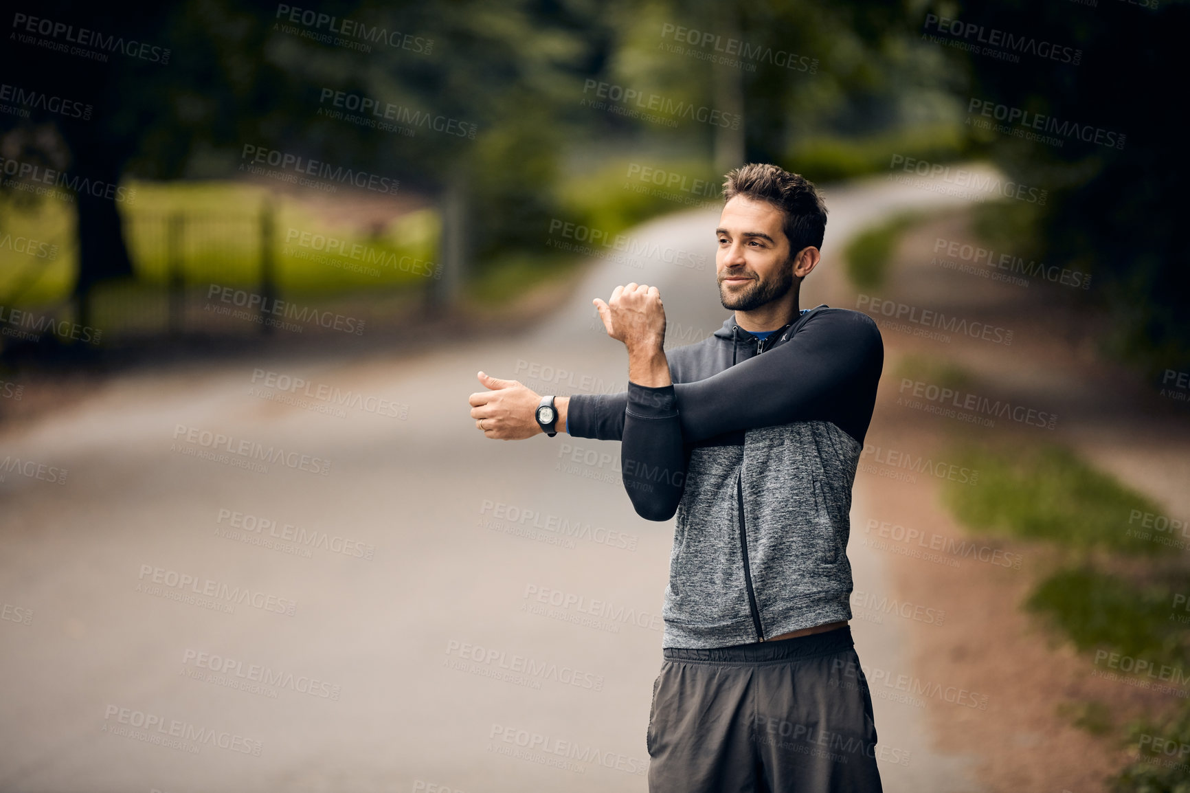 Buy stock photo Shot of a sporty man starting his exercise routine with stretching exercises