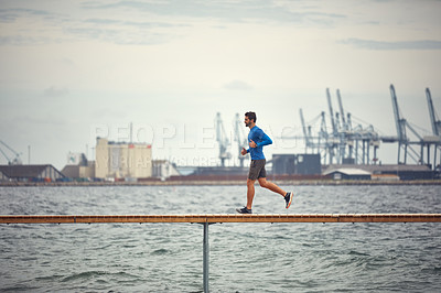 Buy stock photo Shot of a sporty middle-aged man out running by the seaside