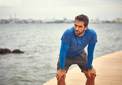 Buy stock photo Shot of a sporty man taking a break after his run