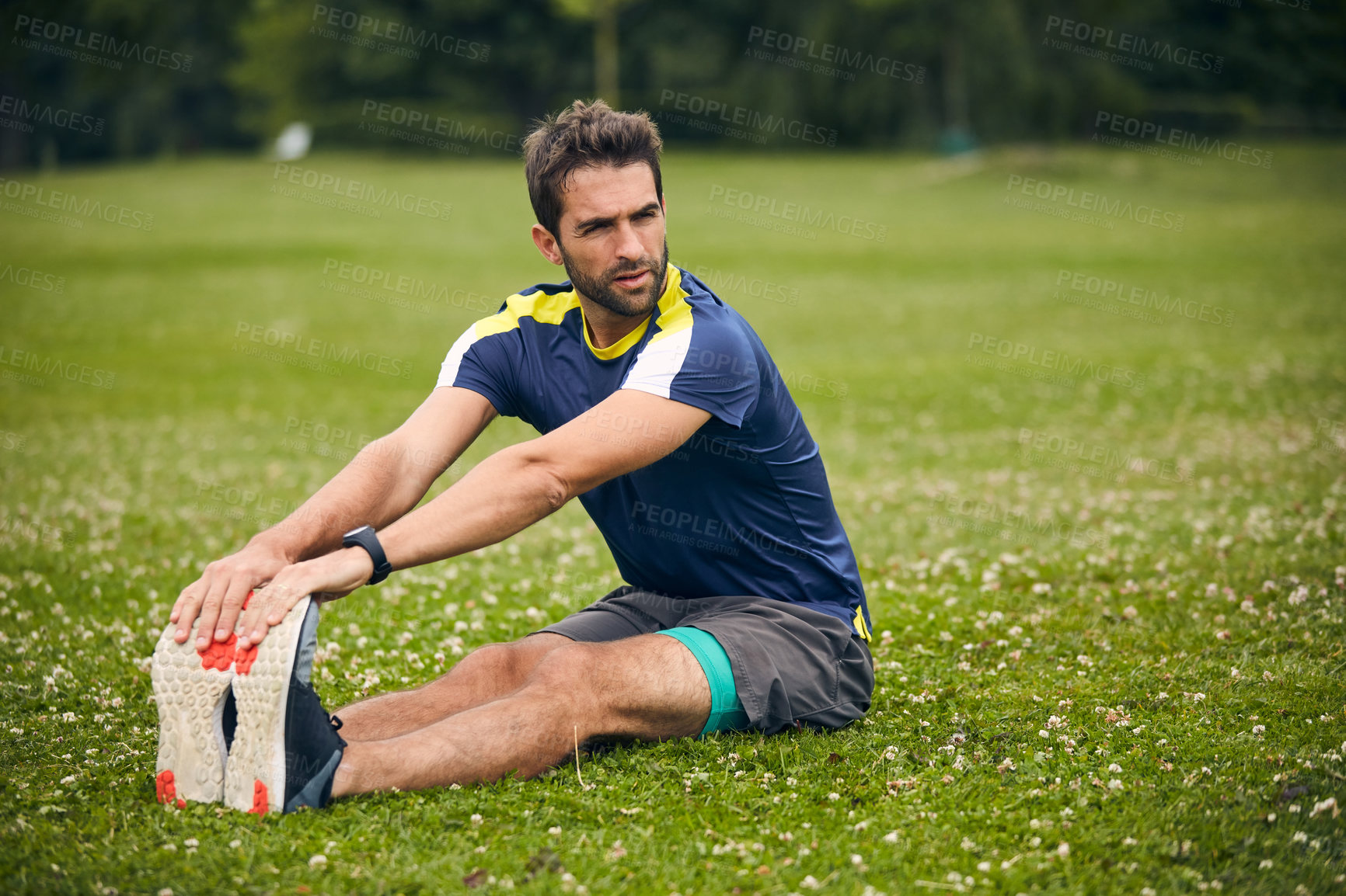 Buy stock photo Shot of a sporty man starting his exercise routine with stretching exercises