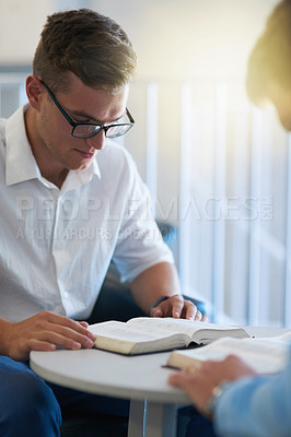 Buy stock photo Shot of two young businessmen reading their bibles at work