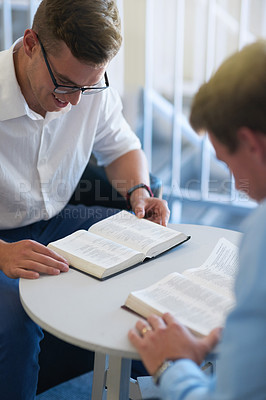 Buy stock photo Shot of two young businessmen reading their bibles at work