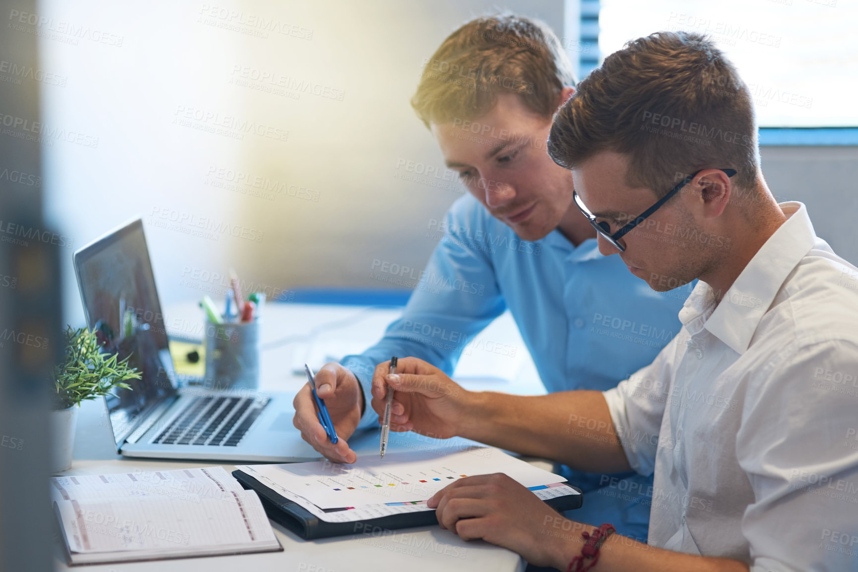 Buy stock photo Shot of two handsome young businessmen working together in their office