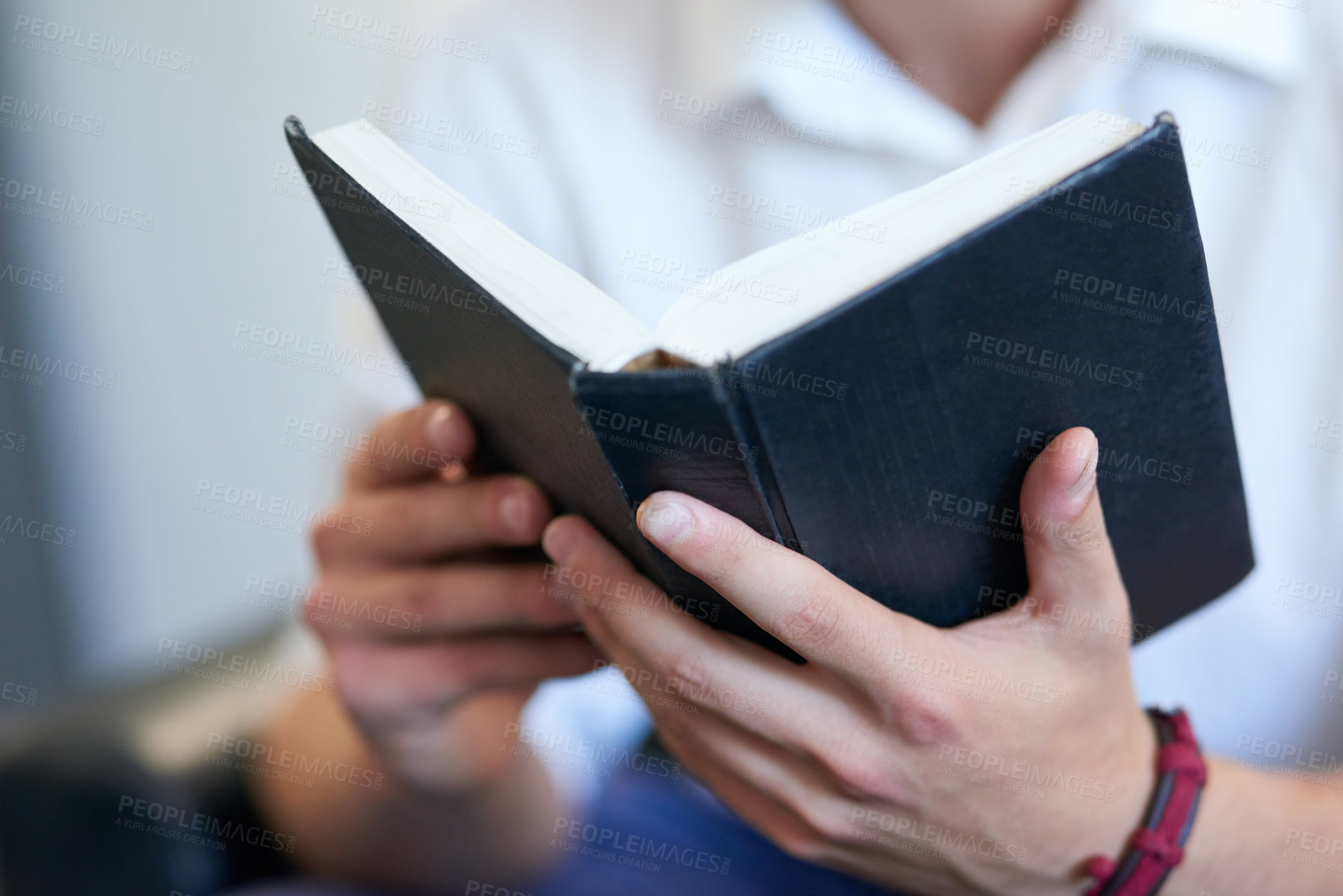 Buy stock photo Shot of an unrecognizable young man reading the bible at work