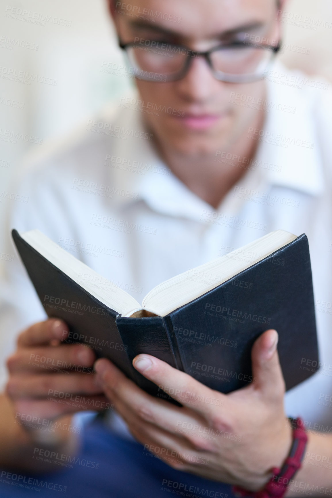 Buy stock photo Shot of a handsome young businessman reading his bible at work