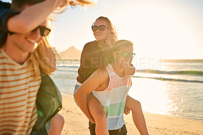 Buy stock photo Cropped shot of two affectionate young men piggybacking their girlfriends at the beach