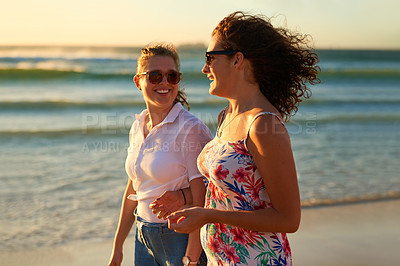 Buy stock photo Cropped shot of two attractive young girlfriends having a chat while strolling on the beach