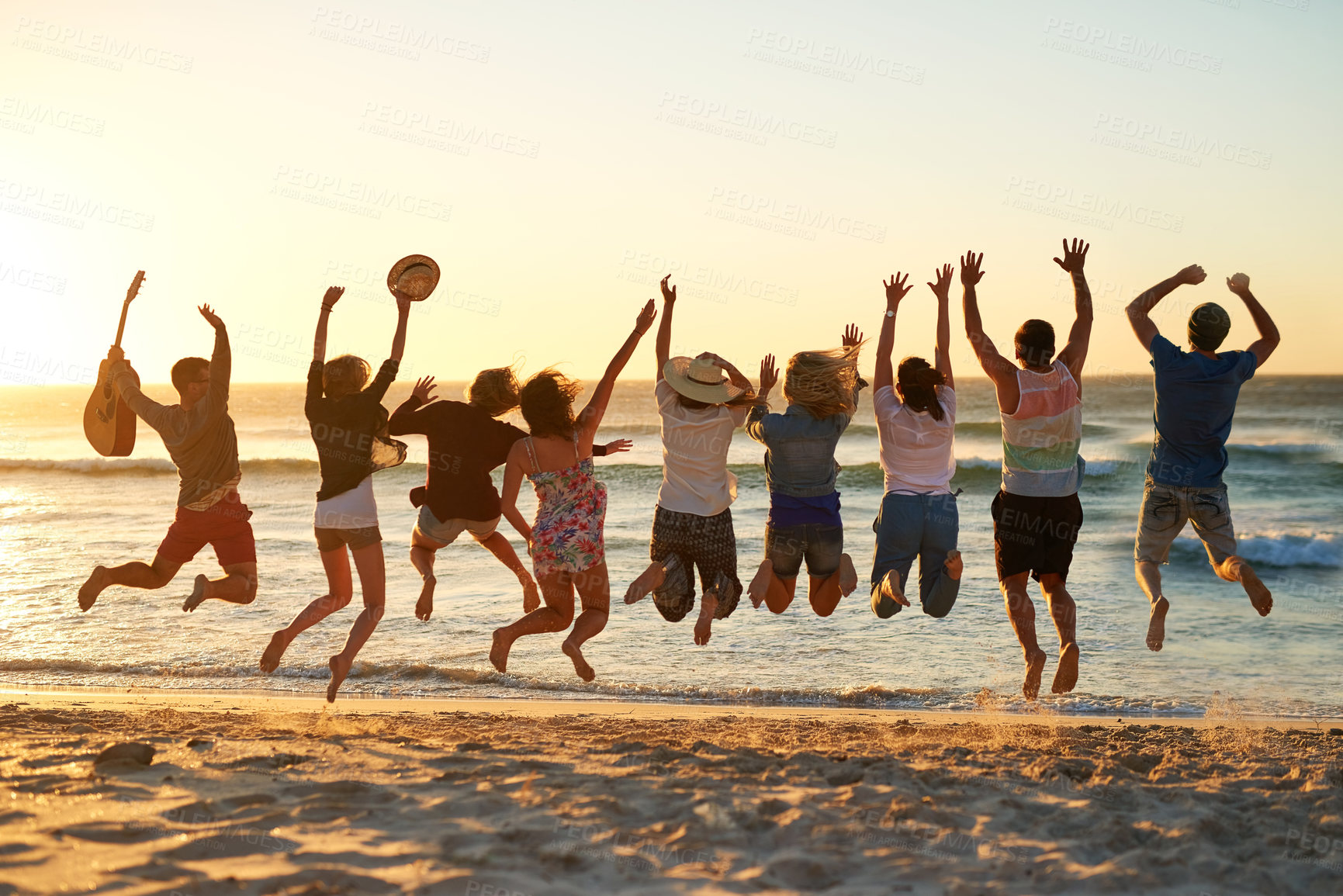 Buy stock photo Rearview shot of a group of young friends jumping into the air at the beach