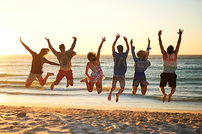 Buy stock photo Rearview shot of a group of young friends jumping into the air at the beach