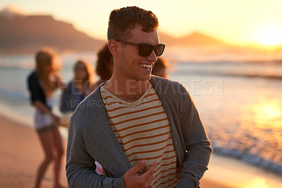 Buy stock photo Cropped shot of a handsome young man smiling while taking a walk on the beach