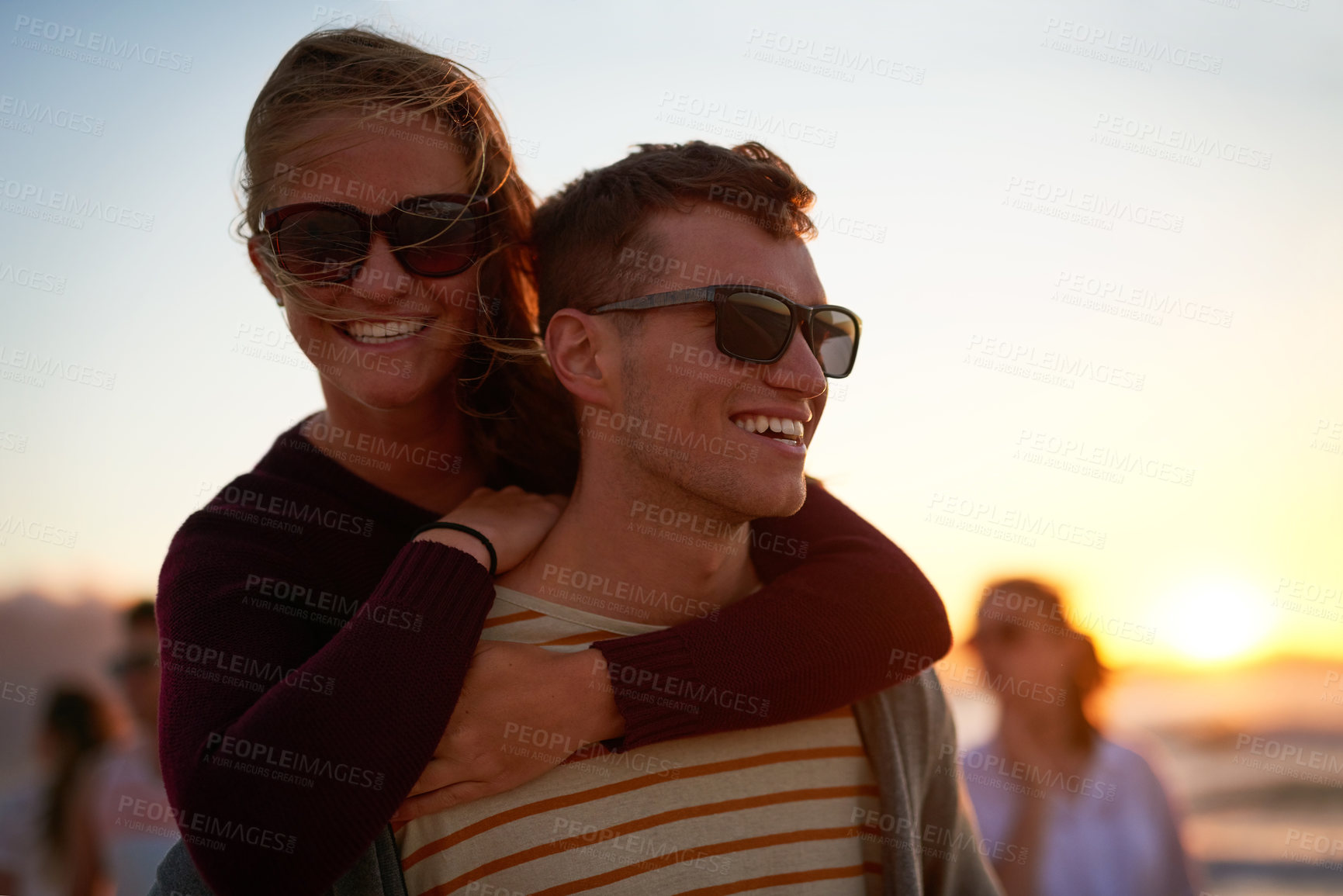 Buy stock photo Cropped shot of an affectionate young man piggybacking his girlfriend on the beach