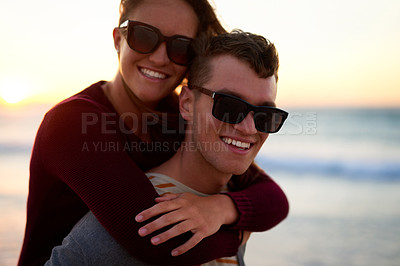 Buy stock photo Cropped portrait of an affectionate young man piggybacking his girlfriend at the beach